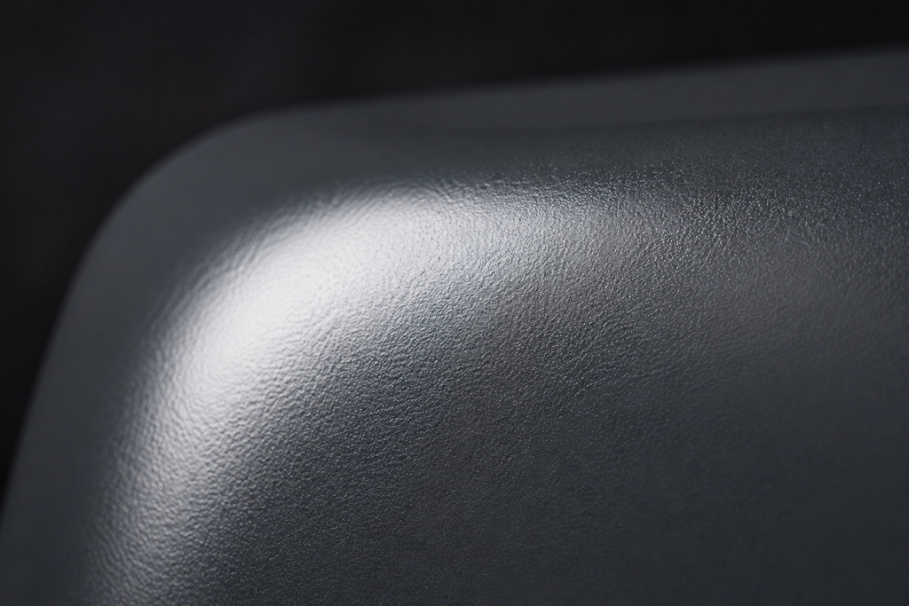 Anthrazitfarbene, hochwertig veredelte Metalloberfläche mit gleichmäßigem Finish und eleganten Lichtreflexionen.
